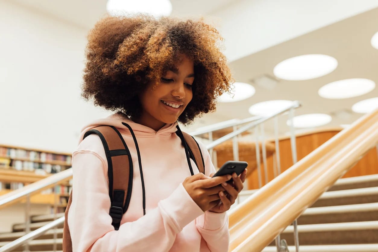 image of high school student using a cellphone in hallway