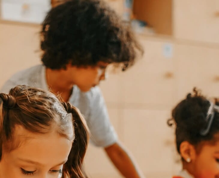 An educator guides two students during a classroom activity