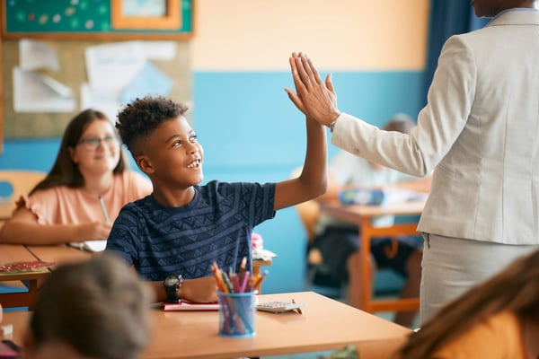 Smiling student high fives teacher in class